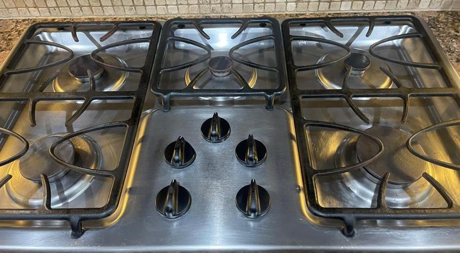 Same stovetop after cleaning, shining grates and knobs